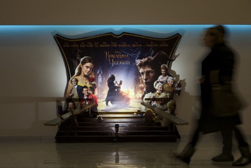 Pria melewati papan promosi film Beauty and the Beast di Rusia. 