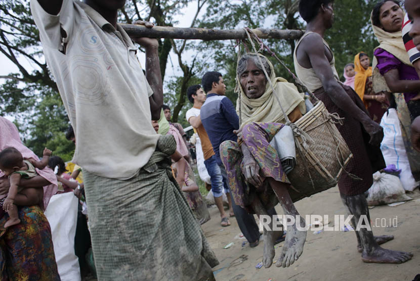 Pria Rohingya membawa ibu mereka yang sakit saat mereka tiba di perbatasan Bangladesh di Teknaf, Bangladesh, Sabtu (9/9). 