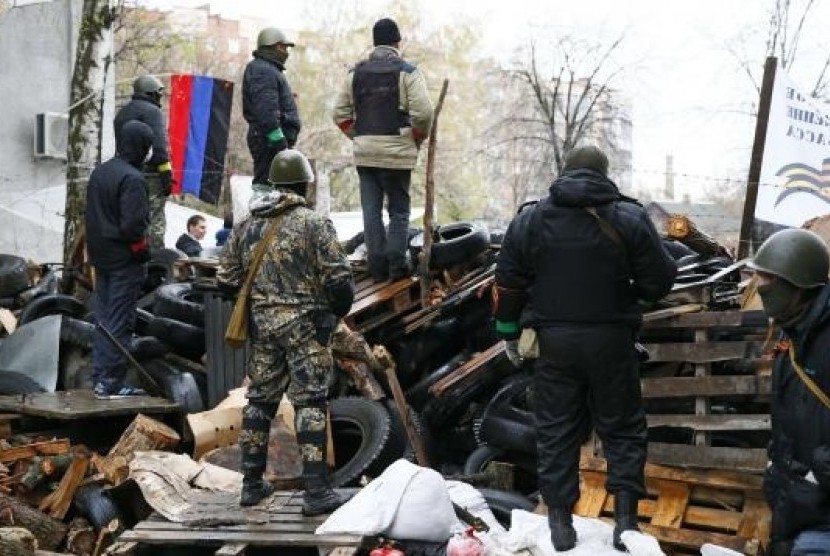 Pro-Russian men stand guard at a barricade near the police headquarters in Slaviansk April 13, 2014. 