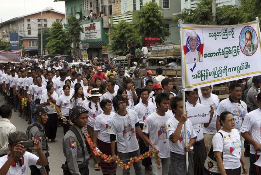 Protesters march with a banner showing pictures of Myanmar President Thein Sein (left) and UN human rights envoy Tomas Ojea Quintana (reading 