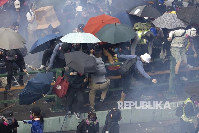 Mahasiswa pengunjukrasa lari saat dibubarkan polisidi area kampus Hong Kong Polytechnic University. Polisi mengepung kampus dengan ratusan mahasiswa pengunjukrasa di dalamnya