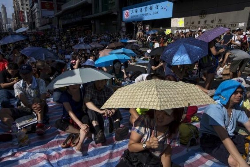 Protesters sit under umbrellas at a main street at Mongkok shopping district after thousand of protesters blocked the road in Hong Kong October 1, 2014. 