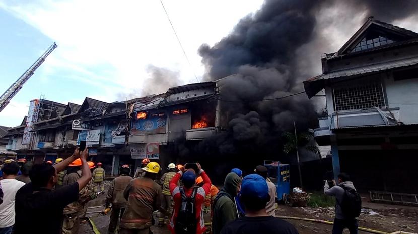 Puluhan masyarakat dan pedagang di Pasar Caringin terlihat menonton kebakaran yang melanda ruko-ruko.