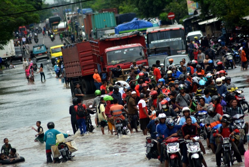 Puluhan truk dan kendaraan bermotor terjebak antrean akibat banjir yang menggenangi kawasan Jalan Raya Pantura Kraton, Pasuruan, Jawa Timur, Kamis (30/6).