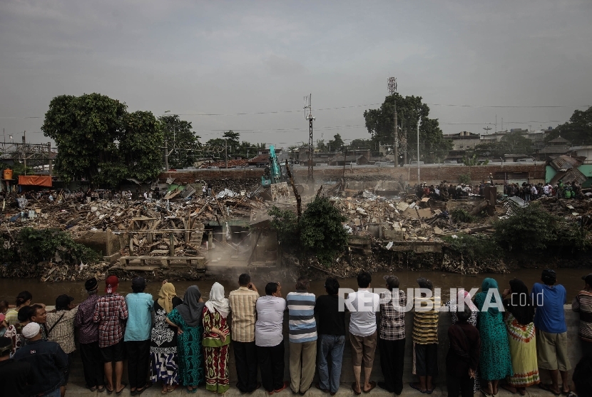 Puluhan warga menyaksikan penggusuran di pemukiman yang terkena proyek normalisasi Sungai Ciliwung, Bukit Duri, Jakarta, Rabu (28/9). 