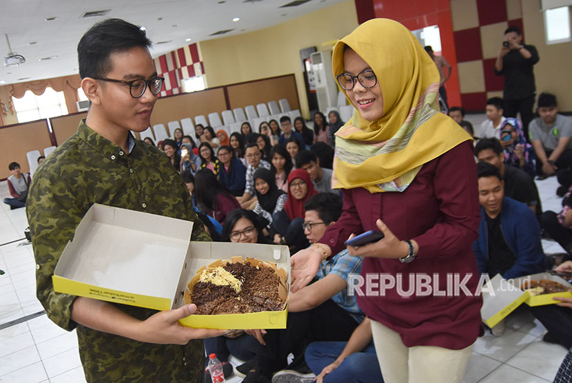 Putra Sulung Presiden Joko Widodo yang juga CEO Markobar, Gibran Rakabuming (kiri) menawarkan martabak manis pada mahasiswa ketika Ngobrol Santai di Universitas Surabaya (Ubaya) Surabaya, Jawa Timur, Sabtu (28/4).