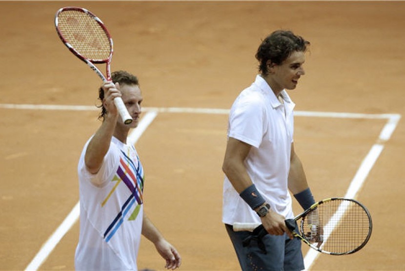 Rafael Nadal (kanan) bersama David Nalbandian meninggalkan lapangan usai menaklukan ganda Spanyol, Pablo Andujar/Guillermo Garcia-Lopez, di putaran pertama turnamen Brazil Terbuka di Sao Paulo, Brazil, Selasa (12/2). 