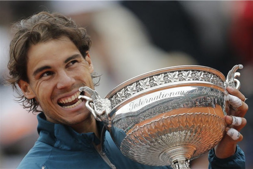 Rafael Nadal, petenis asal Spanyol, menggigit trofi usai mengalahkan petenis sesama Spanyol, David Ferrer, di partai final Prancis Terbuka 2013 di Roland Garros, Paris, Ahad (9/6). 