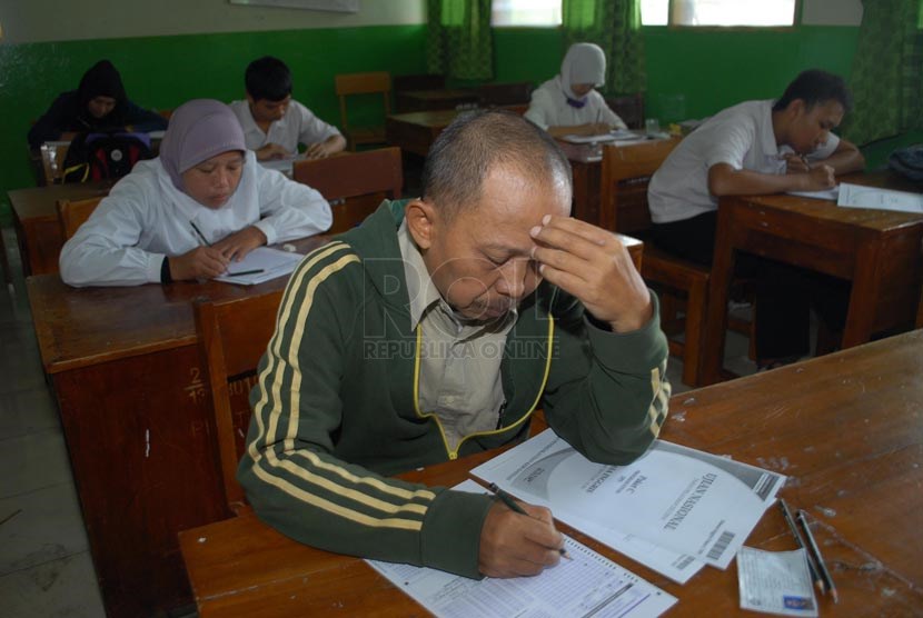 Rafiudin (45) saat mengerjakan ujian paket C di SMPN 216 Jakarta, Rabu (16/4).