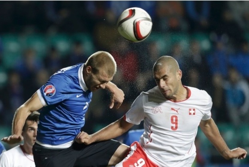 Ragnar Klavan (kiri) berduel dengan pemain Swiss Eren Derdiyok. Klavan mencetak gol bunuh diri yang membuat Swiss mengalahkan Estonia 1-0.