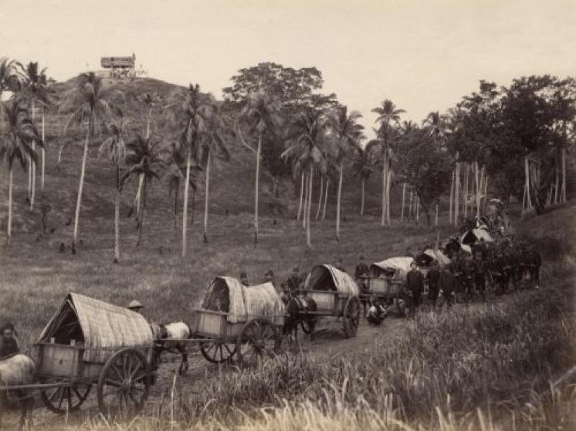 Rangkain gerobak pemasok makanan untuk personil militer kolonial Belanda  yang akan dikirimkan dari  wilayah Indrapoeri ke bivak militer Belanda yang ada Glieng (Aceh) yang berada  di puncak bukit Peng Apih. TGerobak sengaja ditampakkan seperti  sebuah rumah kayu untuk mencegah serangan musuh. Foto dibuat pada  tahunl 1880.