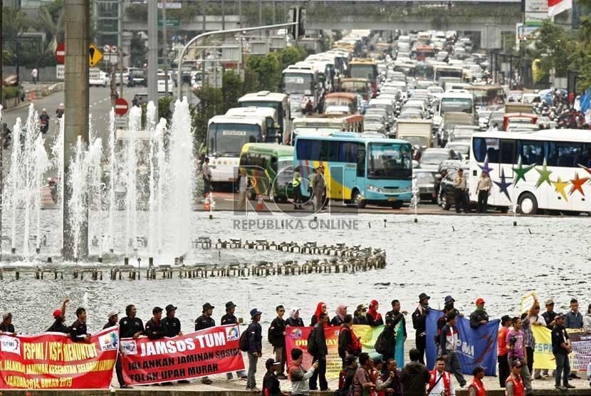   Ratusan kendaraan terjebak kemacetan akibat aksi ribuan buruh yang melakukan long march dari Bundaran Hotel Indonesia menuju Istana Negara di Jalan MH Thamrin, Jakarta Pusat, Rabu (6/2). (Republika/Adhi Wicaksono)