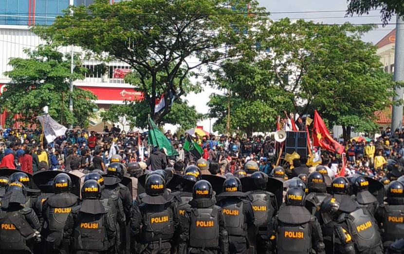 Ratusan massa aksi untuk menolak UU Cipta Kerja berhadapan dengan barikade badan petugas polisi yang berjaga di gerbang utama gedung DPRD Provinsi Jawa Tengah, di Semarang, setelah pintu pagar yang ada di gerbang utama tersebut roboh, Rabu (6/10).