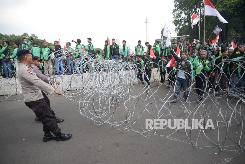  Ratusan pengemudi ojek online (Ojol) melakukan aksi unjuk rasa di depan Istana Merdeka, Jakarta, Selasa (27/3).