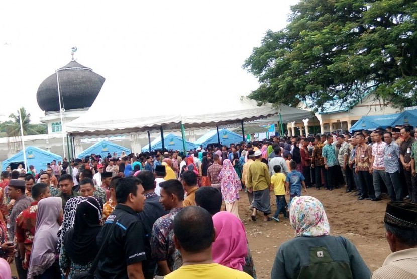 Ratusan warga menunggu kedatangan Presiden Jokowi di masjid At Taqarub, Trienggadeng, Pidie Jaya, Jumat (9/12). Tak sedikit dari mereka yang telah menunggu sejak subuh.