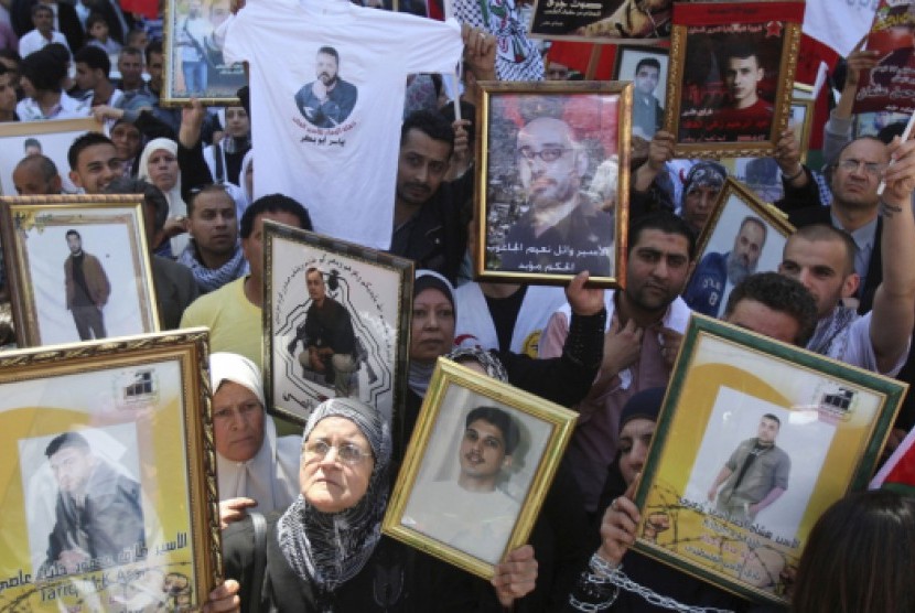 Ratusan warga Palestina memegang foto anggota keluarga mereka yang ditahan di penjara Israel dalam unjuk rasa di Kota Nablus, Tepi Barat, Palestina, Selasa (17/4).