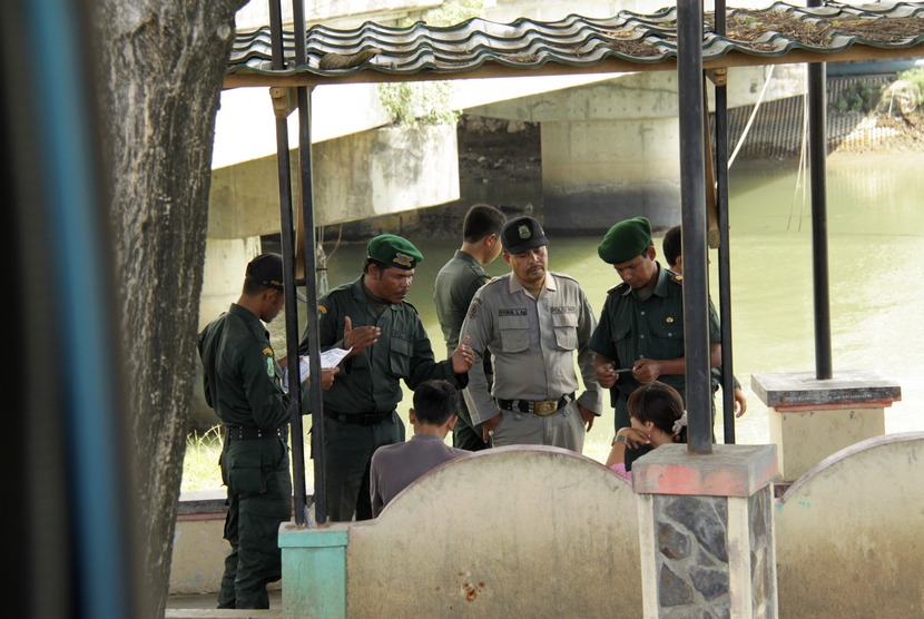 Petugas Wilayatul Hisbah (WH) Dinas Syariat Islam memeriksa pasangan non muhrim yang duduk bersama di lokasi wisata tepi sungai Krueng Aceh, Kuta Alam, Banda Aceh, Senin (22/9).