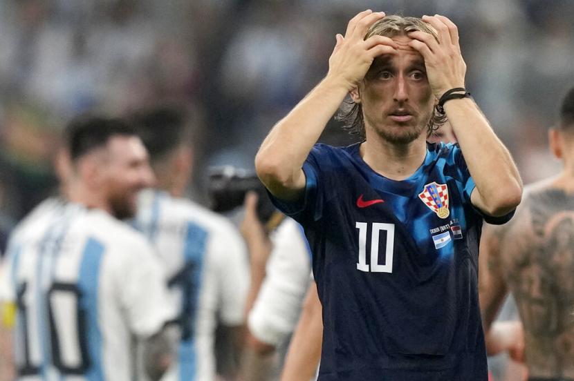  Reaksi Luka Modric dari Kroasia, sementara Lionel Messi dari Argentina (latar belakang kiri) merayakan, pada akhir pertandingan sepak bola semifinal Piala Dunia antara Argentina dan Kroasia di Stadion Lusail di Lusail, Qatar, Rabu (14/12) dini hari WIB.  Argentina menang 3- 0. 