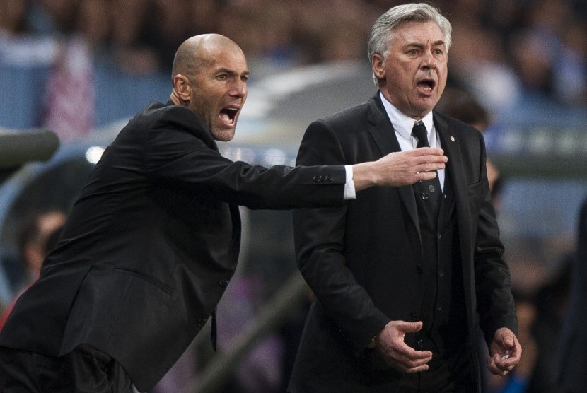 Real Madrid's assistant coach Zinedine Zidane from France, left, and coach Carlo Ancelotti from Italy, right, gesture during a Spanish La Liga soccer match at La Rosaleda stadium in Malaga, Spain, Saturday March 15, 2014. 