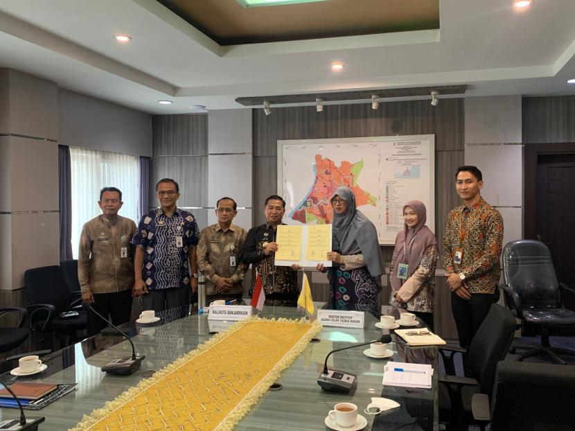 Rektor Institut Agama Islam (IAI)  Tazkia Murniati Mukhlisin (ketiga dari kiri) dan  Walikota Banjarmasin Ibnu Sina (keempat dari kanan) menunjukkan naskah kesepakatan bersama yang ditandatangani kedua belah pihak di  di Kota Banjarmasin, Kamis (9/6). 