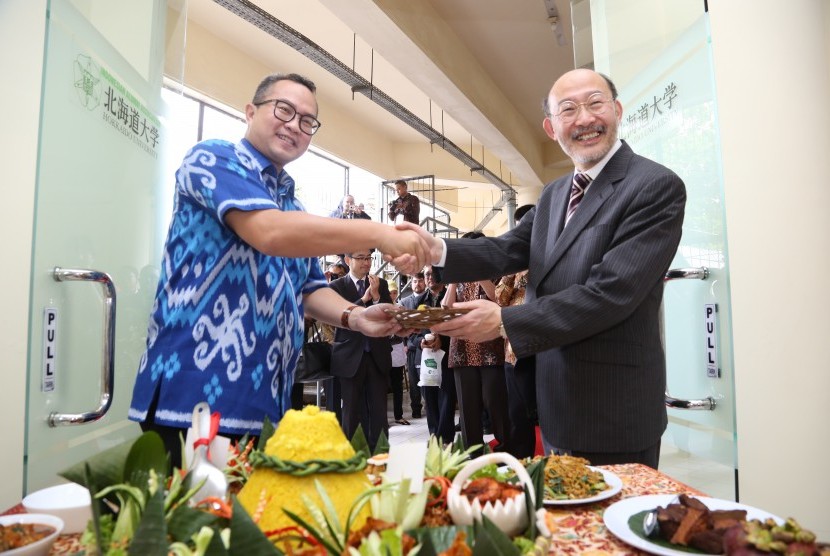 Rektor IPB Arif Satria (kiri) menyerahkan potongan tumpeng kepada Dean of Research Faculty of Agriculture Hokkaido University, Prof Atsushi Yokota.