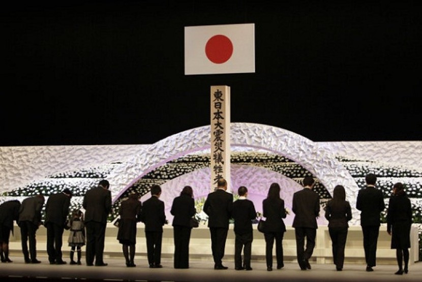 Relatives of of the March 11, 2011 earthquake and tsunami victims offer chrysanthemums during the national memorial service to pay tribute to those who lost their lives in the disaster in Tokyo, Monday, March 11, 2013. 