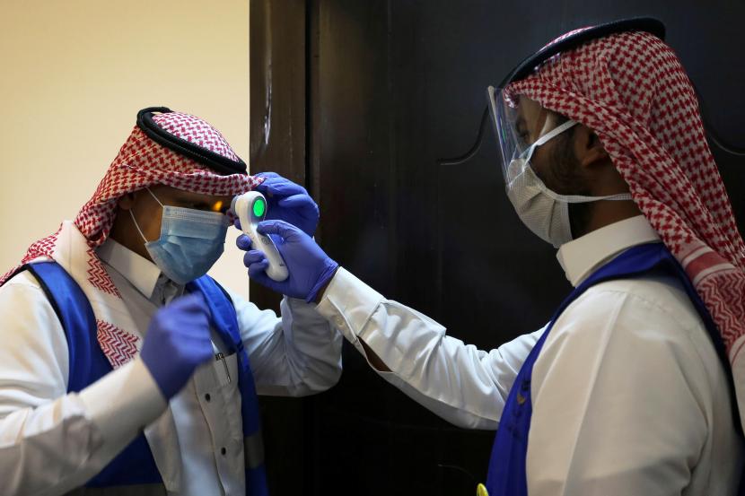 Ilmuwan Arab Saudi Kembangkan Vaksin Covid-19 Halal. Relawan Arab Saudi memeriksa suhu tubuh rekannya menyusul pandemi virus Covid-19 di Riyadh, Arab Saudi, 10 Mei 2020.
