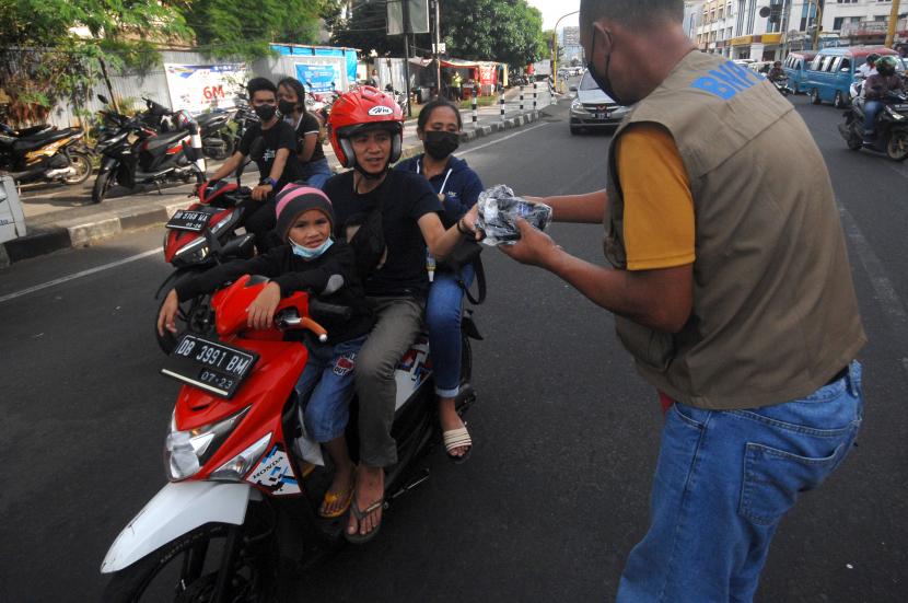 Relawan Badan Nasional Penanggulangan Bencana (BNPB) membagiakan masker kepada pengendara.