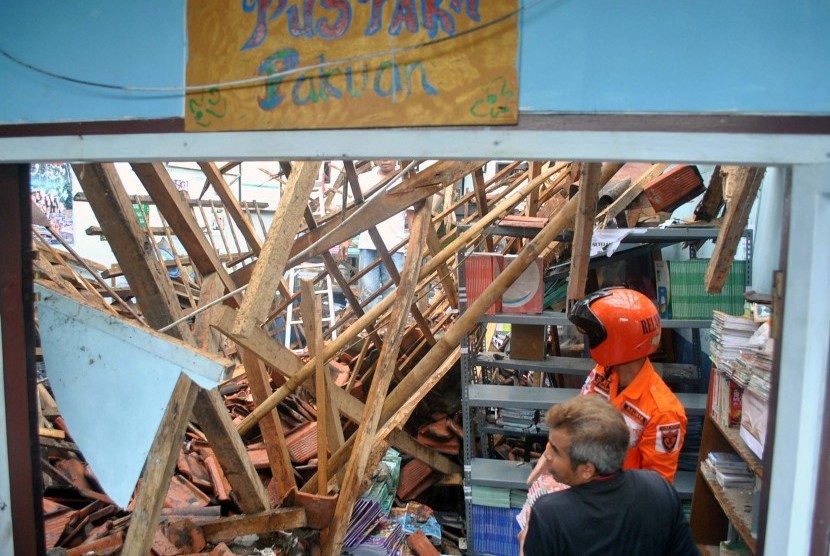 Relawan Badan Penanggulangan Bencana Daerah (BPBD) Kota Bogor dan petugas sekolah mengangkat buku pelajaran dari ruang perpustakaan yang ambruk di SDN Pakuan, jalan Dahlia, Kelurahan Pakuan, Kota Bogor, Jawa Barat, Minggu (12/2). 