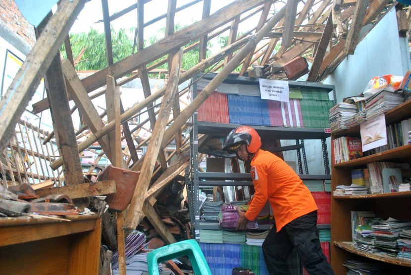 Relawan Badan Penanggulangan Bencana Daerah (BPBD) Kota Bogor mengangkat buku pelajaran dari ruang perpustakaan yang ambruk di SDN Pakuan, jalan Dahlia, Kelurahan Pakuan, Kota Bogor, Jawa Barat, Minggu (12/2).