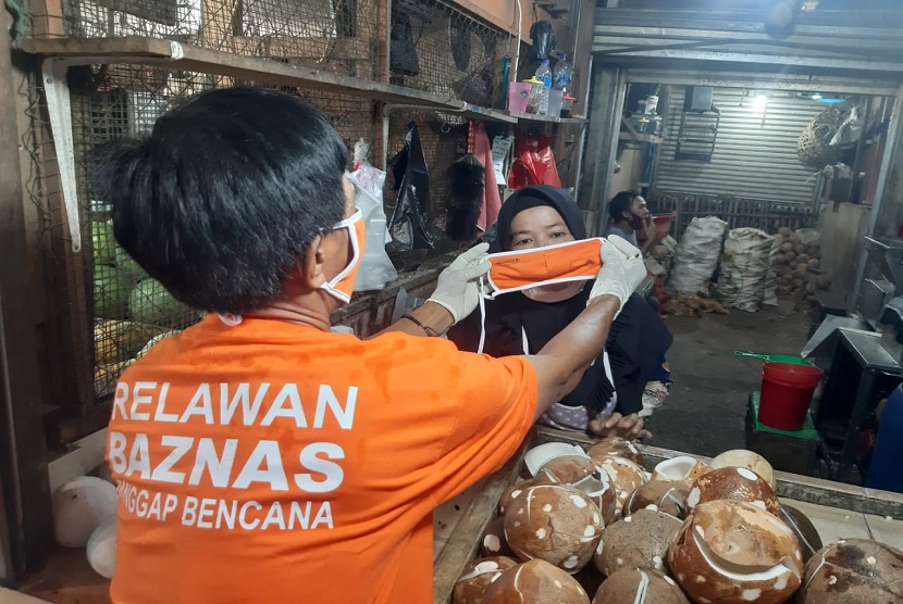 Relawan Baznas membagikan paket masker dan hand sanitizer untuk pedagang di pasar tradisional Harapan Jaya, Bekasi, Senin (13/4).