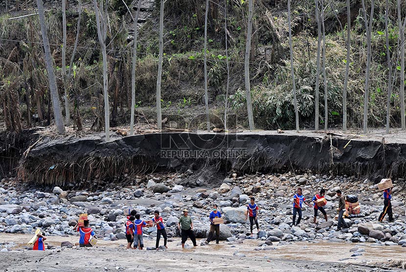 Relawan berusaha mengirimkan bantuan melalui sungai yang terputus akses jalannya akibat lahar dingin Gunung Kelud yang terputus akses jalannya akibat lahar dingin Gunung Kelud di Dusun Klangon, Malang, Jawa Timur, Kamis (20/2).