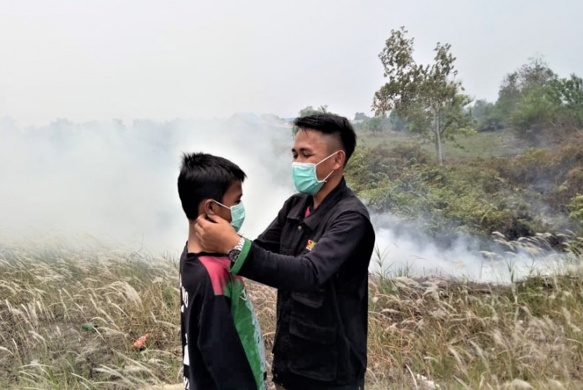 Relawan BMH memakaikan masker kepada seorang bocah korban asap di Palangkaraya.