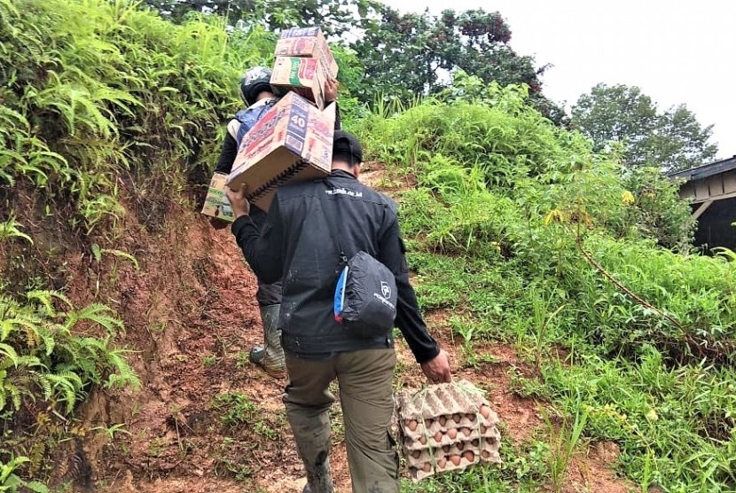 Relawan BMH menyusuri jalanan licin dengan memanggul bantuan dan menenteng telur untuk korban musibah tanah longsor di Desa Sejati, Mamuju.