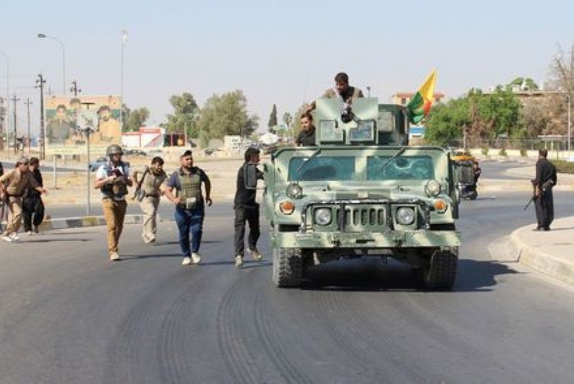 Relawan dan pasukan Peshmerga Kurdi membawa senjata di utara Kirkuk.