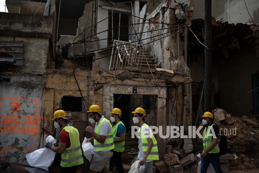 Relawan dari American University of Beirut berjalan di samping bangunan yang hancur di lingkungan dekat lokasi ledakan pekan lalu yang melanda pelabuhan Beirut, Lebanon, Kamis (13/8/2020). 