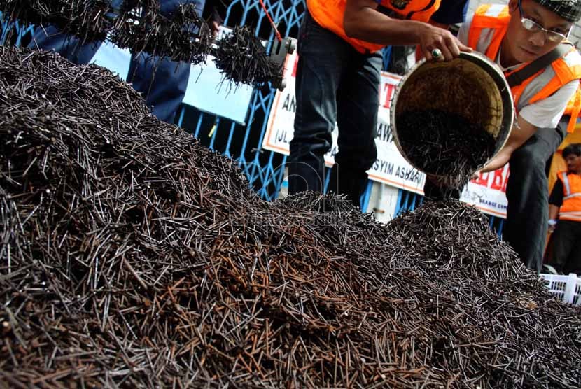  Relawan Komunitas Semut Orange menggelar ribuan paku hasil razia ranjau paku di Jalan KH Hasyim Ashari di Jakarta, Ahad (5/1).  (Republika/Yasin Habibi)