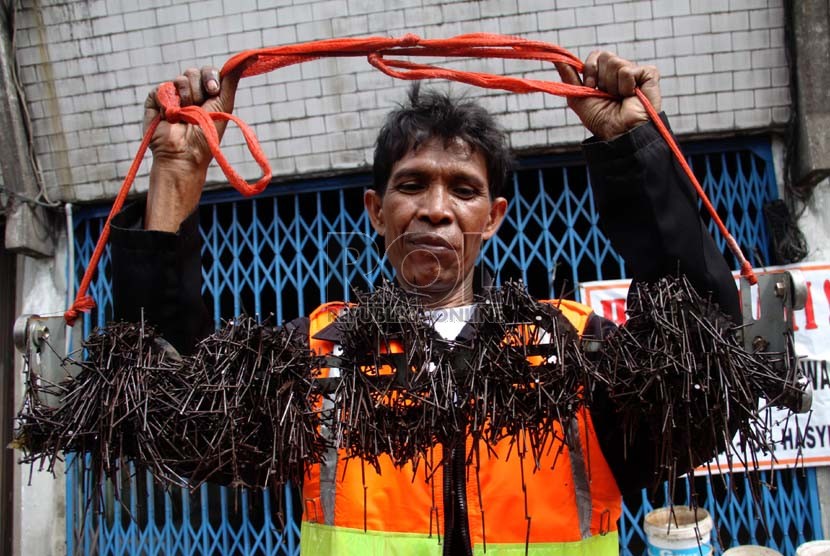  Relawan Komunitas Semut Orange menggelar ribuan paku hasil razia ranjau paku di Jalan KH Hasyim Ashari di Jakarta, Ahad (5/1).  (Republika/Yasin Habibi)