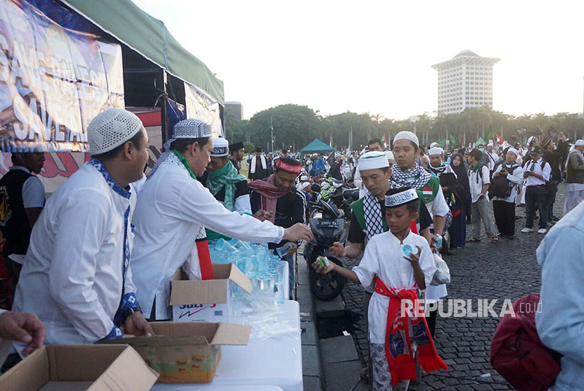 Relawan membagikan makanan dan minuman kepada peserta aksi bela Palestina di kawasan Monas, Jakarta, Ahad (17/12)