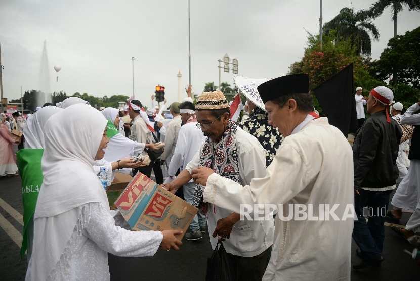 Relawan membagikan makanan dan minuman kepada peserta aksi super damai 212 di Jalan MH Thamrin, Jakarta, Jumat (2/12). Jutaan umat menghadiri aksi 212 yang menuntut agar tersangka kasus penistaan agama Basuki T Purnama alias Ahok ditahan.