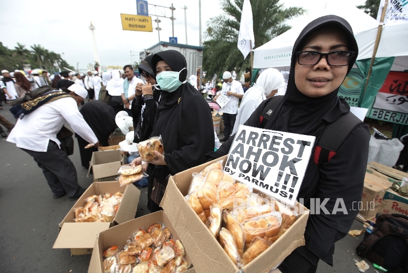 Relawan membagikan makanan gratis kepada para peserta sebagai bentum dukungan terhadap aksi Super Damai 212 di kawasan silang Monas, Jakarta,Jumat (2/12). 