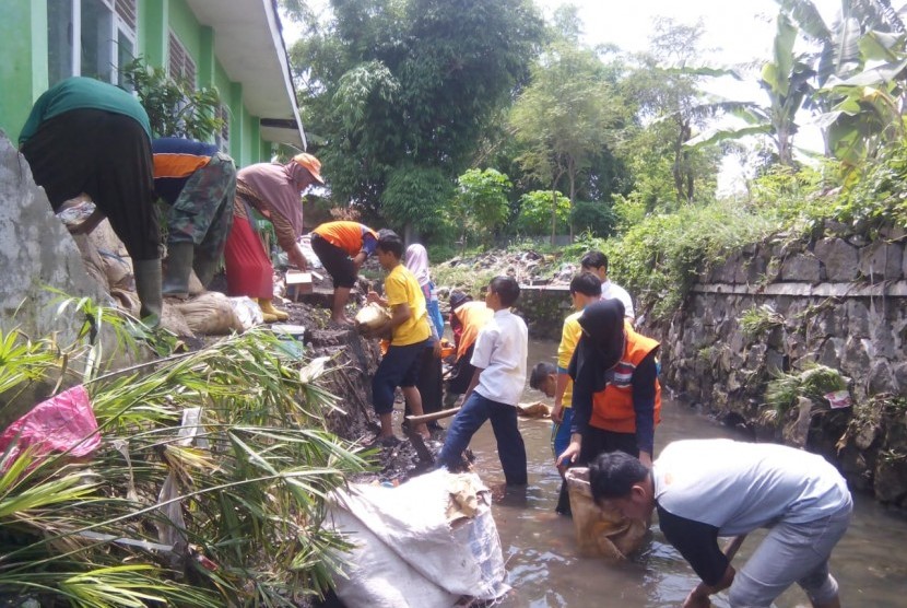 Relawan membantu membersihkan sekolah binaan Rumah Zakat yang terkena banjir.
