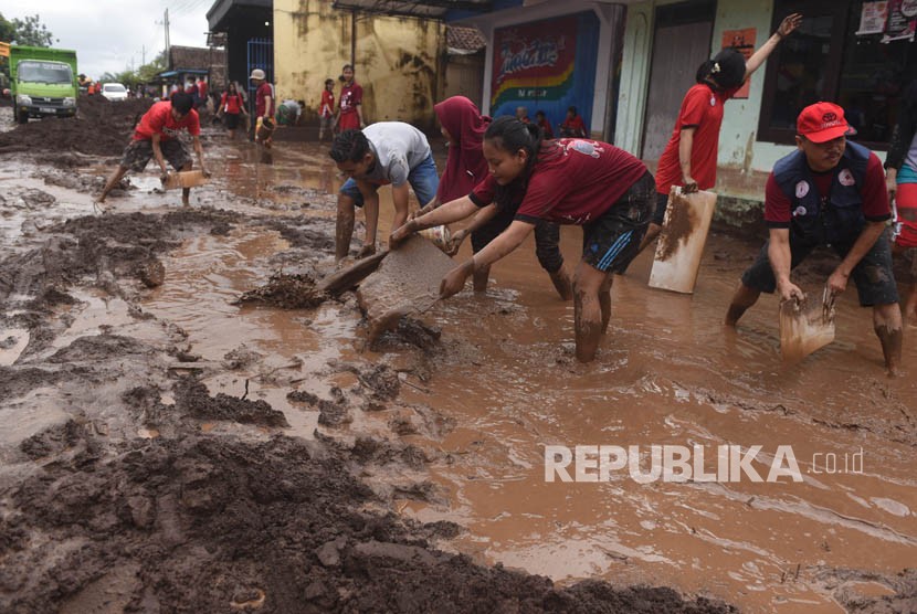 Relawan membersihkan endapan lumpur di lokasi dampak banjir / Ilustrasi 