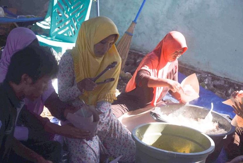 Relawan membungkus nasi untuk dibagikan kepada pengungsi korban gempa bumi Lombok di dapur umum tempat pengungsian di Pemenang, Lombok Utara, NTB, Minggu (12/8). 