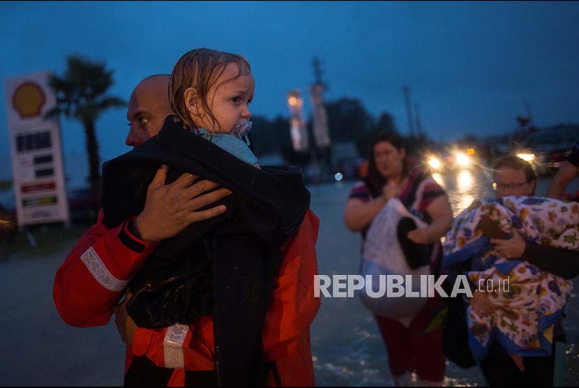 Relawan  mengevakuasi warga menuju tempat yang lebih tinggi di kawasan Tidwell Road di Houston Timur, Texas,