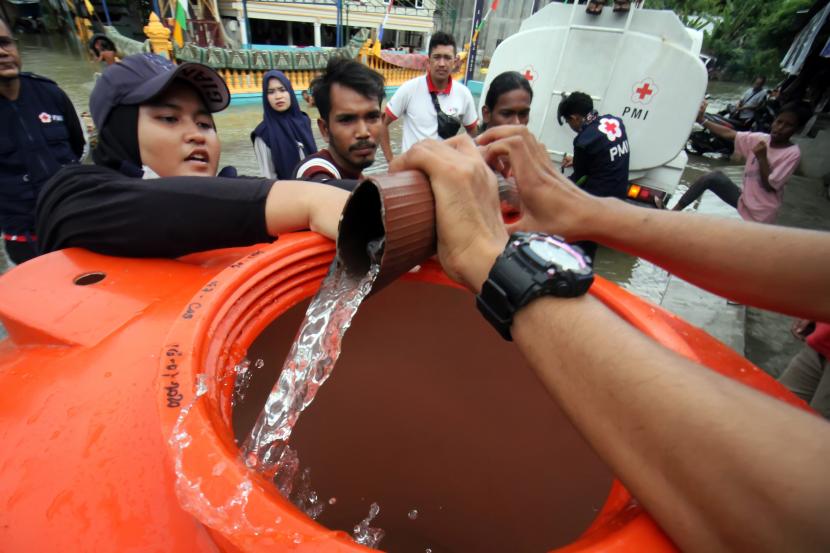 Relawan Palang Merah Indonesia (PMI) membagikan air untuk warga terdampak banjir di Desa Ketapang, Aceh Utara, Aceh, Kamis (6/1/2022). PMI Aceh Utara memberikan bantuan air bersih, kain sarung, selimut, kelambu dan pakaian laik pakai kepada korban banjir di daerah tersebut.