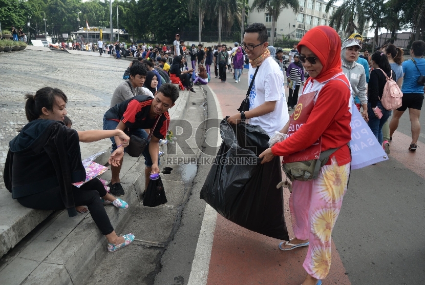  Relawan peduli Jakarta Bersih membersihan sampah yang berserakan di kawasan Hari Bebas Kendaraan Bermotor (HBKB) di Bundaran HI, Jakarta, Ahad (20/12). (Republika/Yasin Habibi)