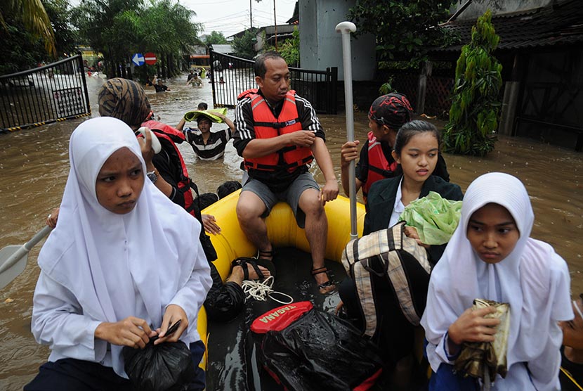 Relawan Tagana menggunakan perahu karet mengantar warga dan pelajar menuju rumah mereka yang terendam banjir di Perumahan Bukit Cengkeh II, Cimanggis, Depok, Jawa Barat, Jumat (12/2).(Antara/Indrianto Eko Suwarso)
