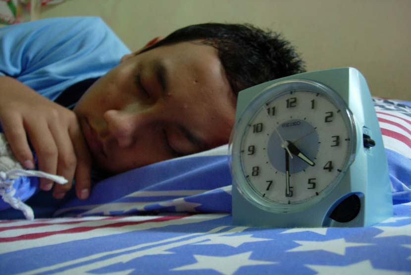 Remaja Laki laki tidur dengan menggunakan jam beker (ilustrasi).