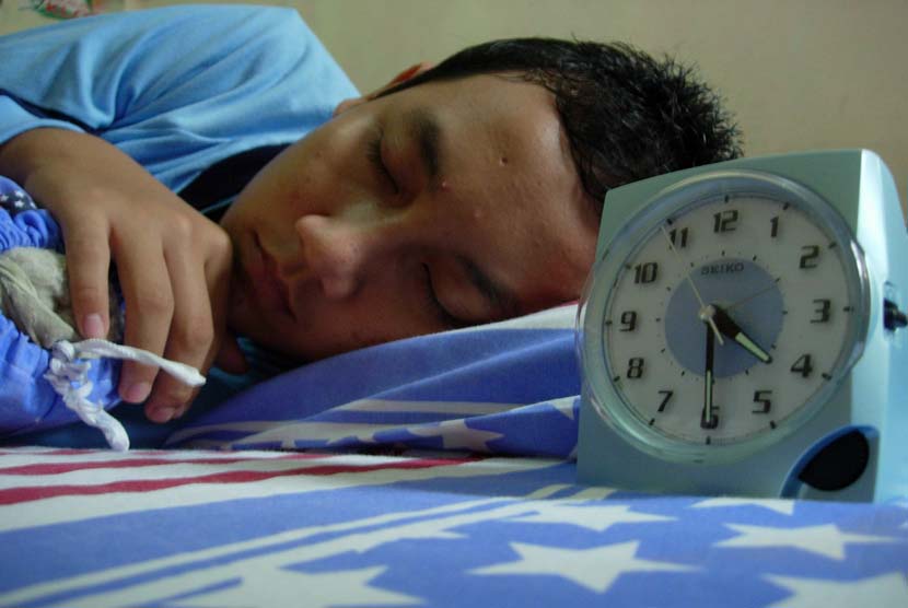 Remaja Laki laki tidur dengan menggunakan jam beker (ilustrasi).